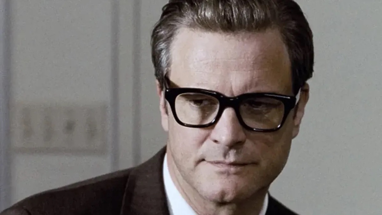 Colin Firth wears horn-rimmed black glasses and his hair slicked back.