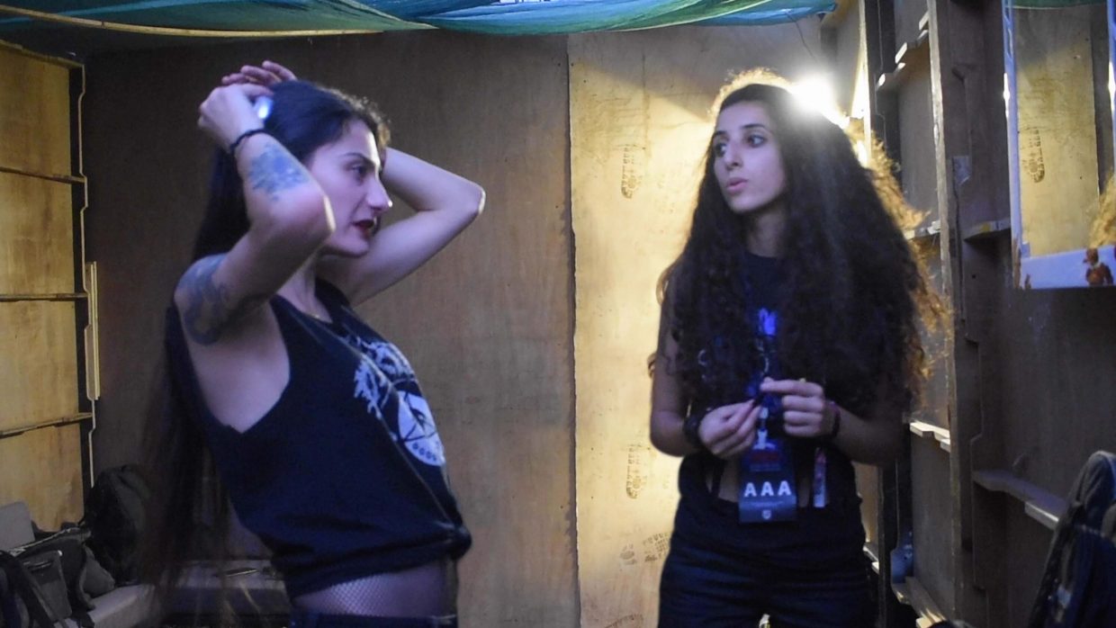 Two women with black hair and black t-shirts in a room with yellow walls