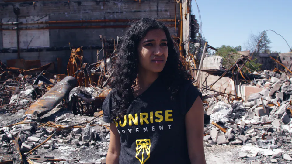 A woman, Sunrise Movement activist Varshini Prakash, at a site destroyed by fire