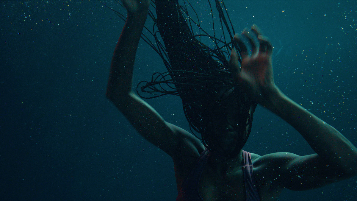 A Black woman submerged in blue-tinted water