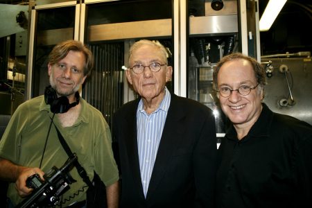 Three white men standing in a film laboratory