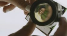 A picture of a Black woman seen through the lens of a photo magnifying glass