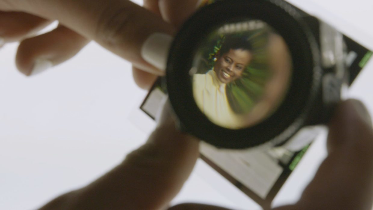 A picture of a Black woman seen through the lens of a photo magnifying glass