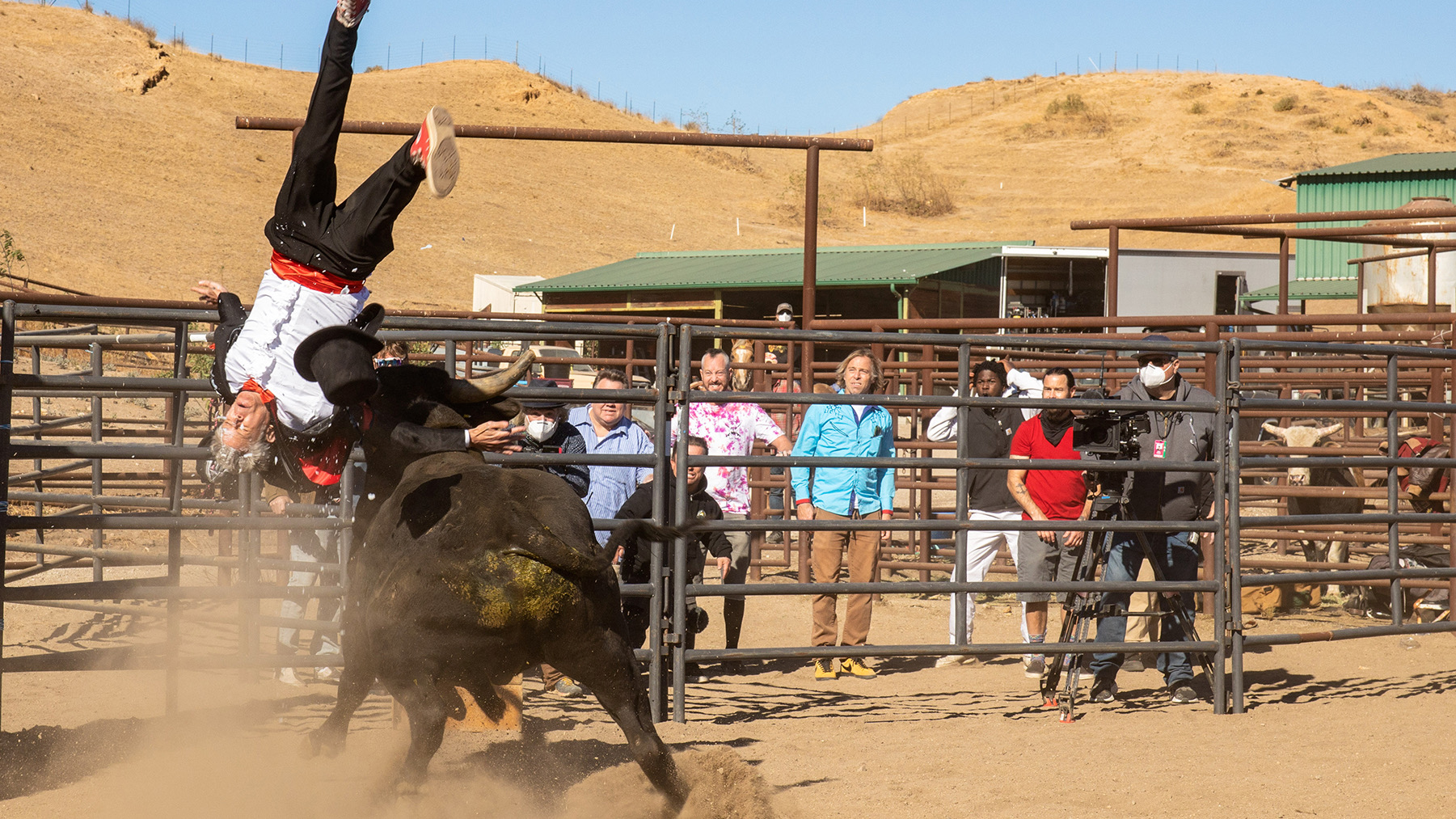 A man flying in the air after being thrown by a bull in a rodeo arena