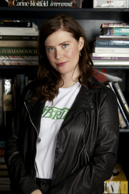 A white woman with reddish brown hair wearing a black jacket and Variety t-shirt