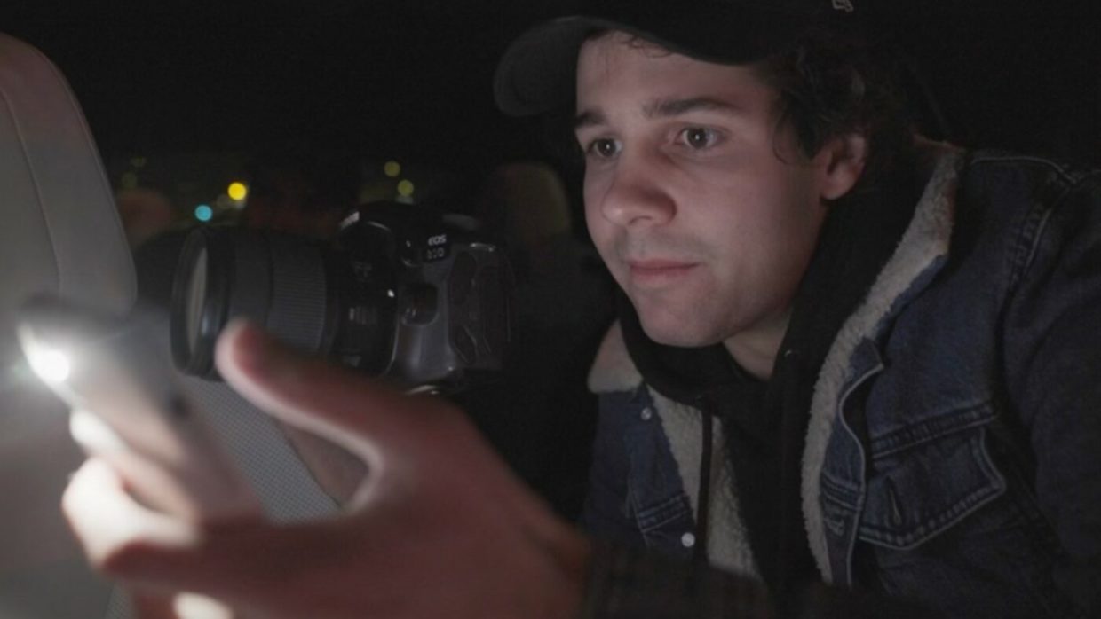 A young man with brown hair looking at a phone screen