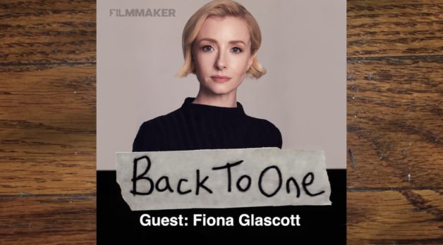 A young white woman -- actor Fiona Glascott -- in a black top against a neutral backdrop