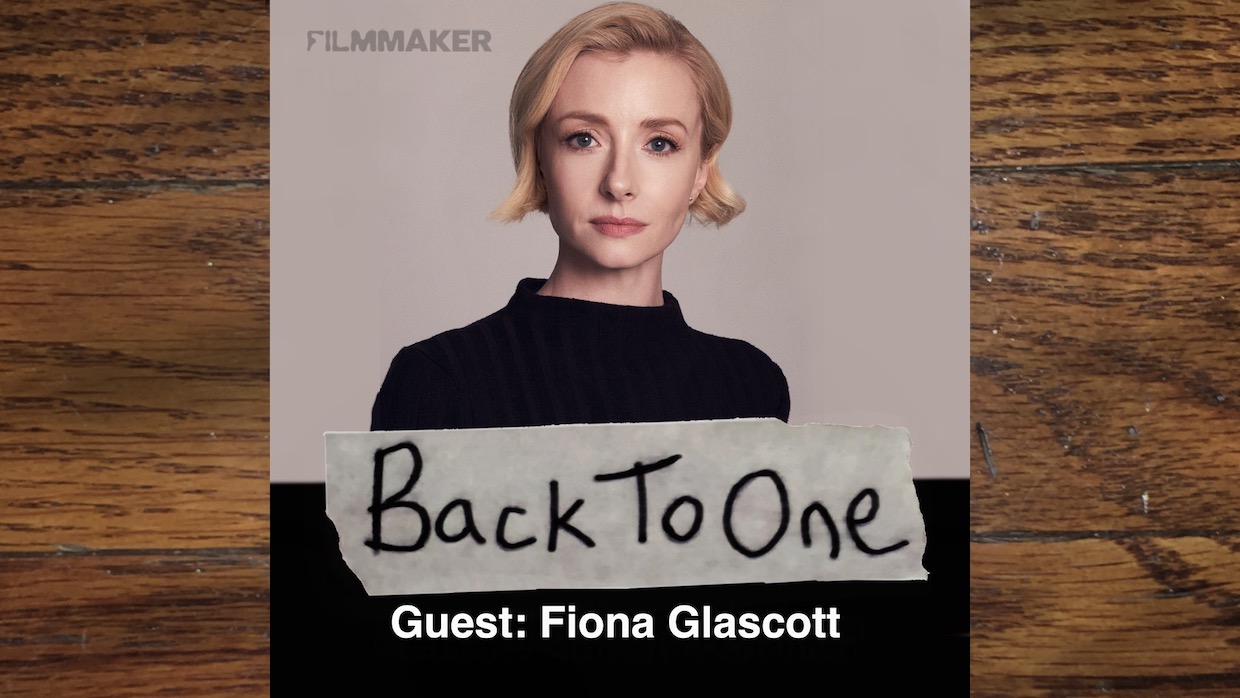 A young white woman -- actor Fiona Glascott -- in a black top against a neutral backdrop