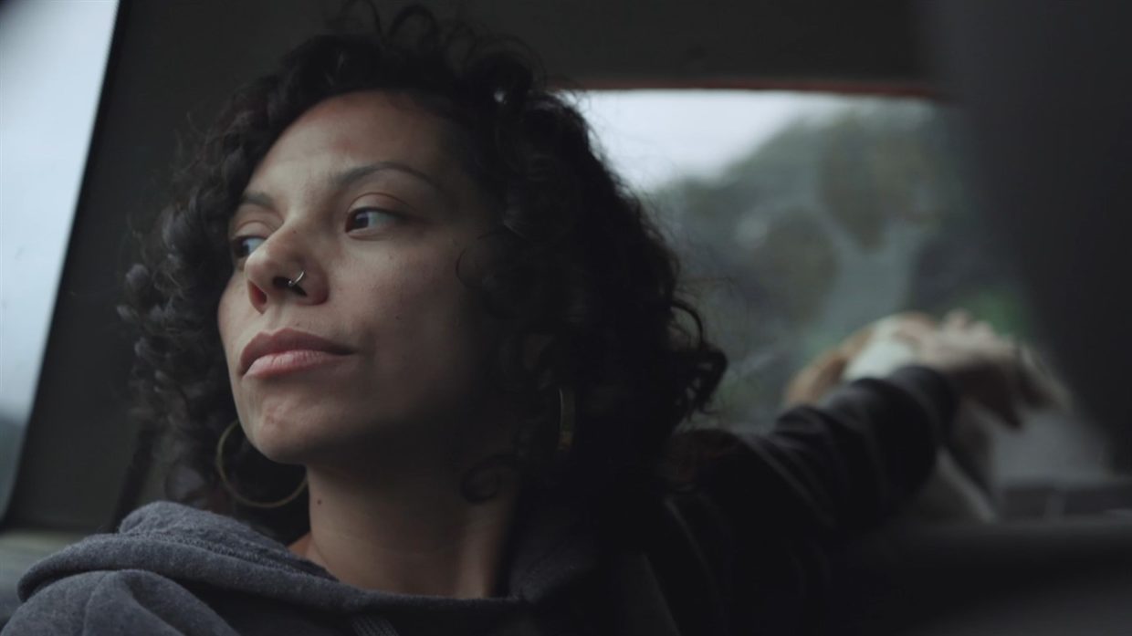 A dark haired woman peering out a car window