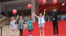 Four children holding balloons on the red carpet of the Cannes Film Festival