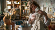 A middle-aged white female sculptor working in her studio