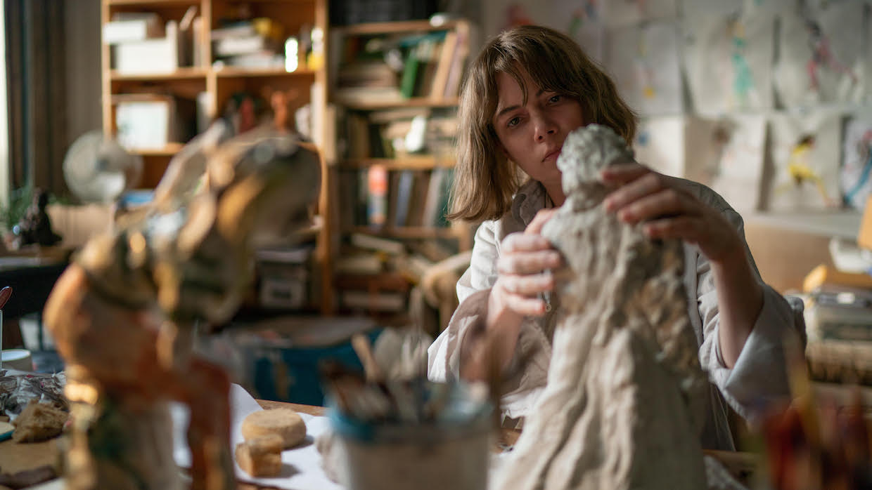 A middle-aged white female sculptor working in her studio