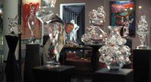 Detective Benoit Blanc (Daniel Craig) stands in a room surrounded by glass figurines on black pedestals.