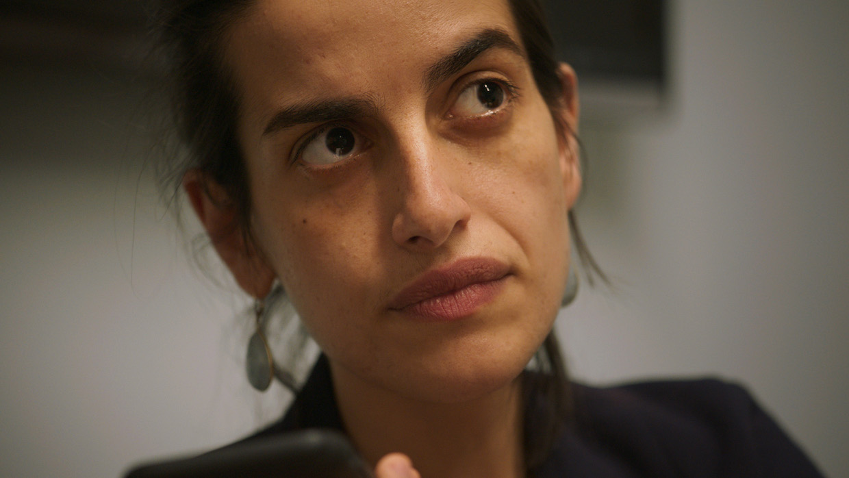 A woman with her brown hair tied back looks up and to the right.