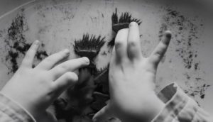 A child's hands are shot in a black and white photograph.