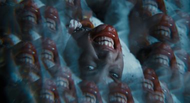 A kaleidoscopic image of a girl's face, her teeth are bared and her mouth is covered in blood.