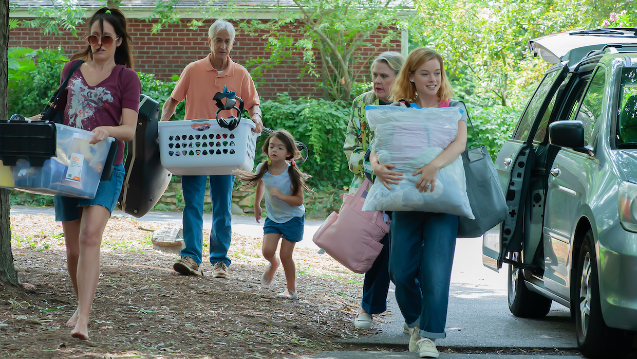 A family unpacks a mini van and carries their belongings into a new home.