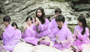 Japanese AUM cult members sit in prayer wearing pink robes.