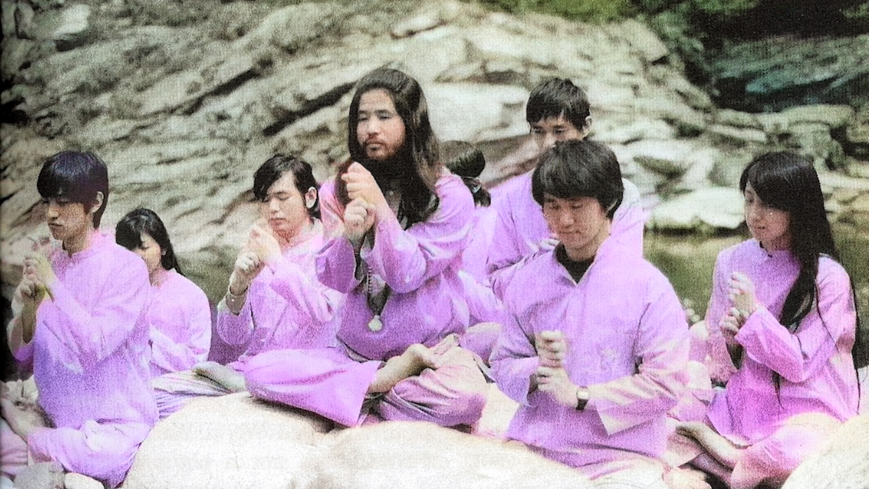 Japanese AUM cult members sit in prayer wearing pink robes.