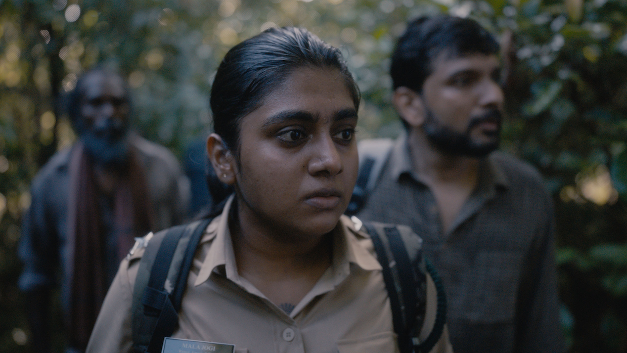 A group of Indian wildlife conservationists stand together in the jungle brush.