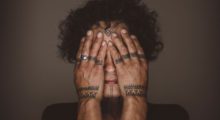 Aaju Peter covers her eyes and shows off her Indigenous hand tattoos in the documentary Twice Colonized.