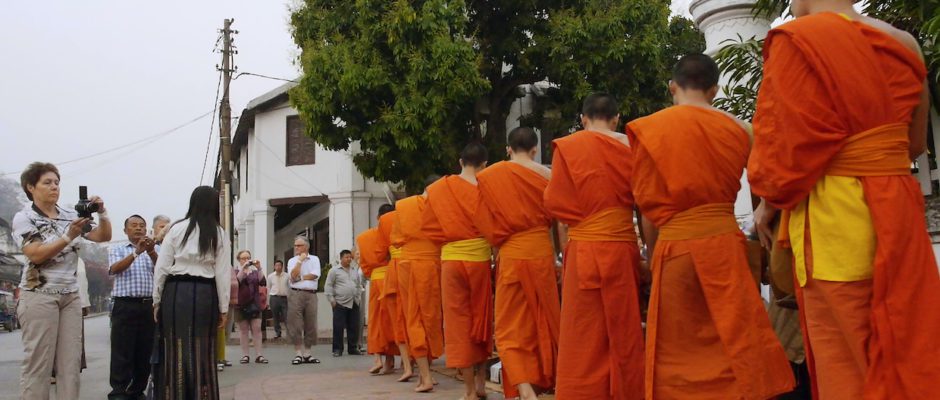 A tourist photographs monks in Laos in Kimi Takesue's Onlookers