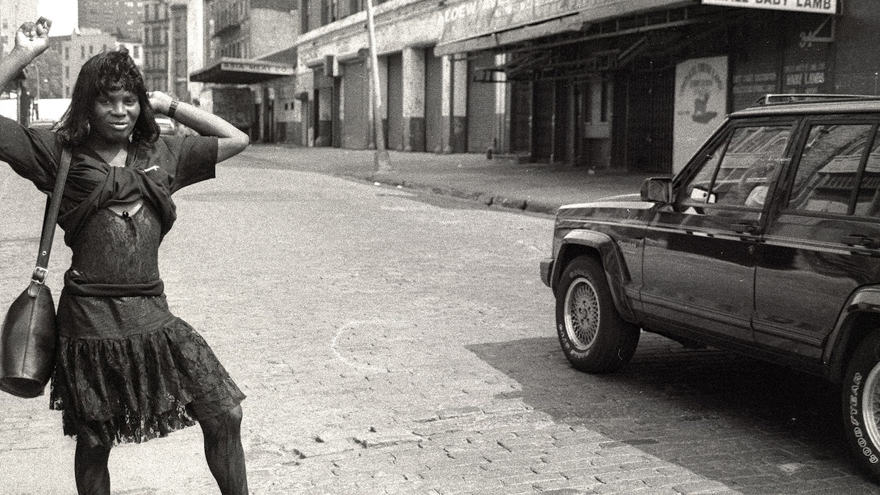 a Black trans woman sex worker poses in an '80s-era dress in an archival image from the 1980s of "The Stroll" in the Meatpacking District of Manhattan.