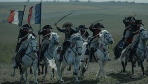 A French cavalry ride with swords drawn and two French flags waving in the wind as they charge.