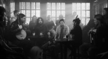 A black and white image of musicians gathered in an Irish pub.