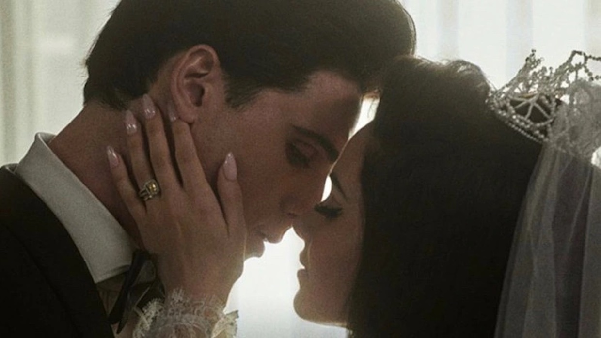 A man and woman, both with dark hair, lean in for a kiss on their wedding day.