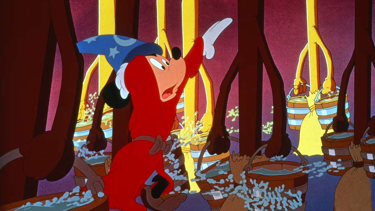 Mickey Mouse dons a red cloak and blue wizard hat as animated brooms carry pails of water.
