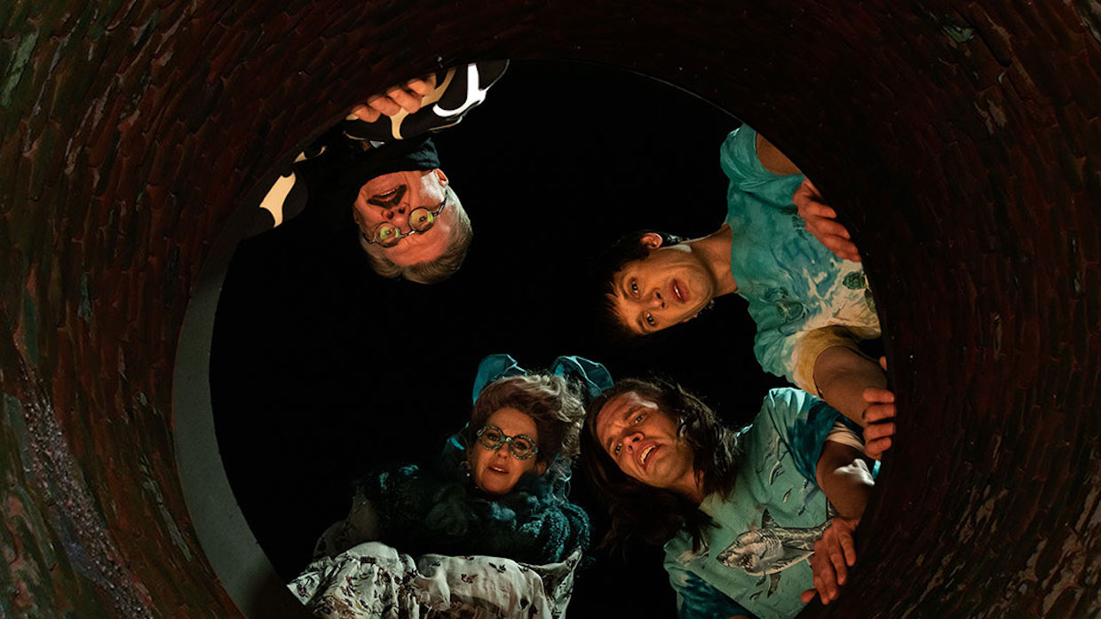 Four people peer down a well at night.