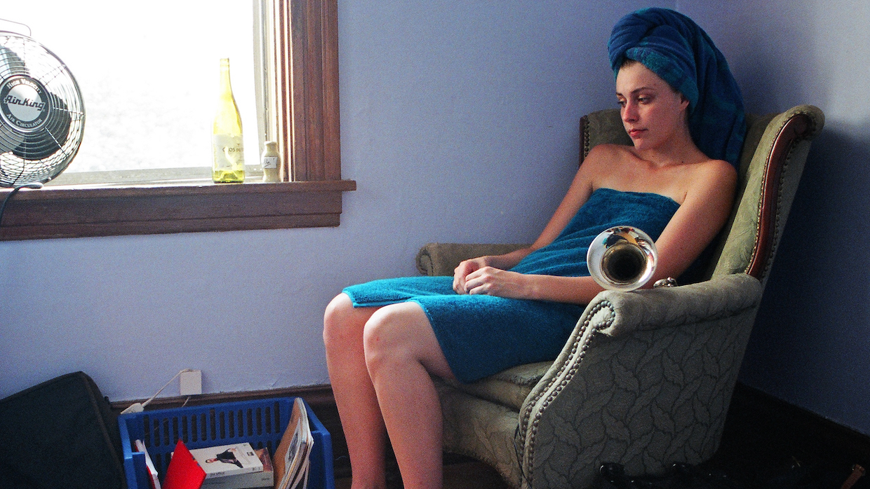 A woman sits in a chair wrapped in a blue bath towel with a matching one wrapped around her head.