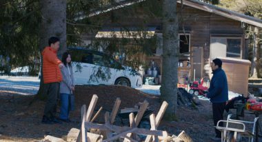 Takahashi (Ryuji Kosaka) points at a pile of wood alongside his colleague Mayuzumi (Ayaka Shibutani) and local resident Takumi (Hitoshi Omika) in Evil Does Not Exist