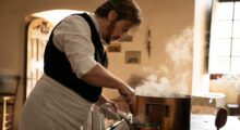 Benoît Magimel labors over a stove and seaming saucepan in The Taste of Things