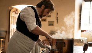 Benoît Magimel labors over a stove and seaming saucepan in The Taste of Things