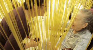 Filmmaker Rea Tajiri bends over her mother, who is sitting in a wheelchair.