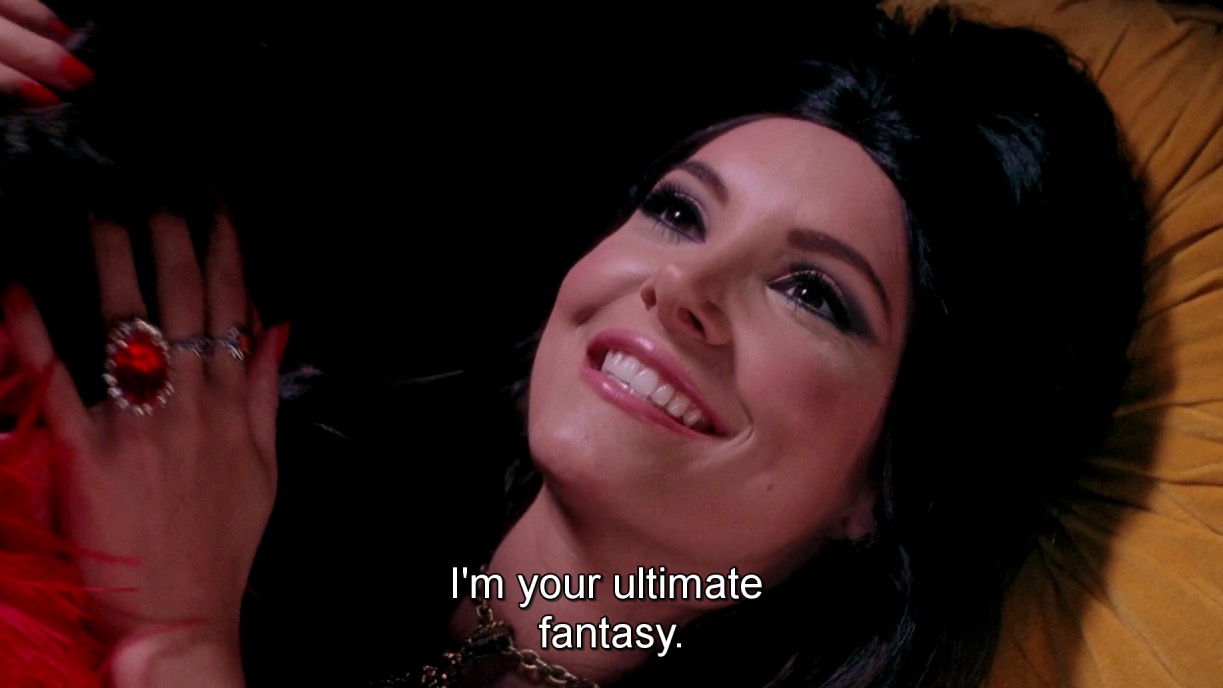 A woman with dark hair smiling and saying the words, "I'm your ultimate fantasy."