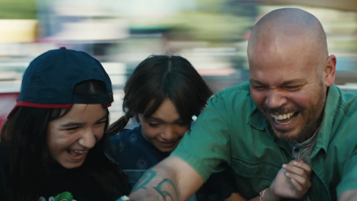 One man in a green shirt and his two daughters are laughing