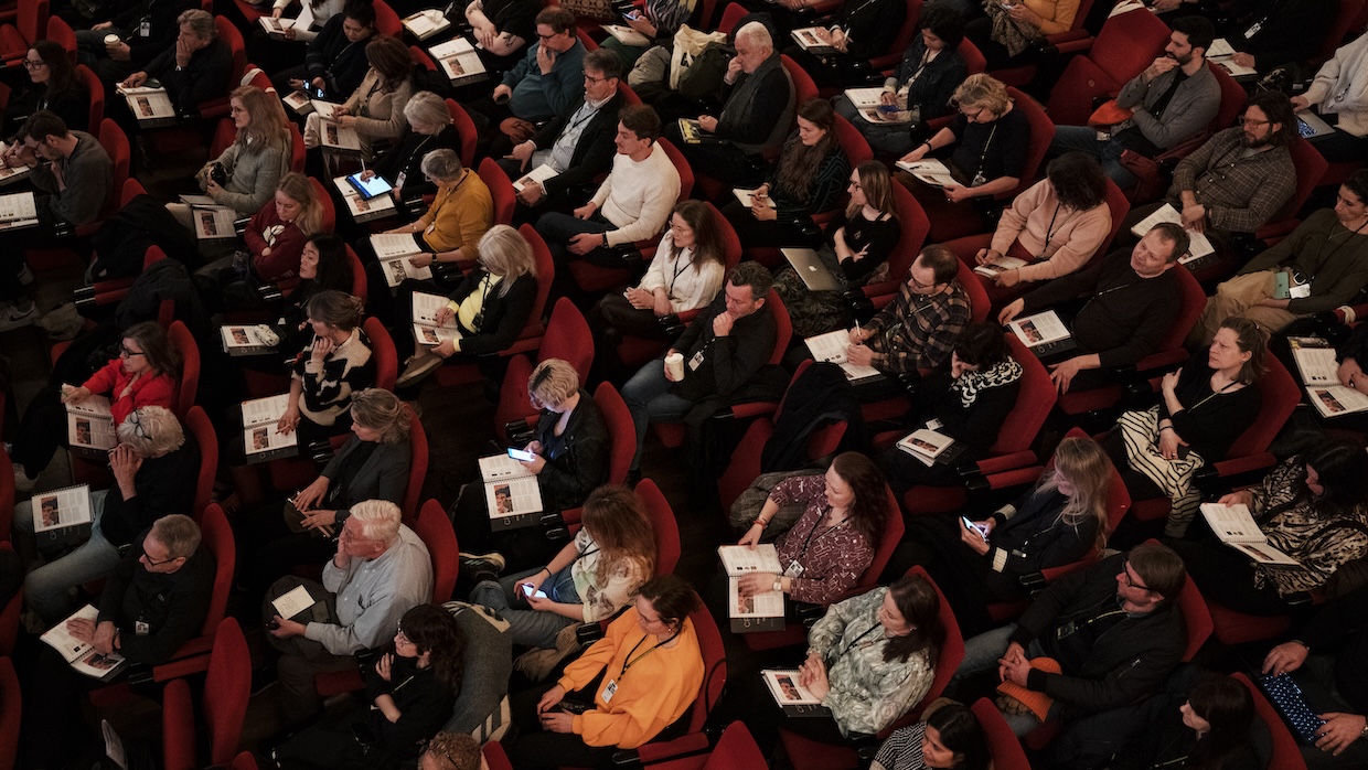 An overhead view of a seated audience in a large auditorium.