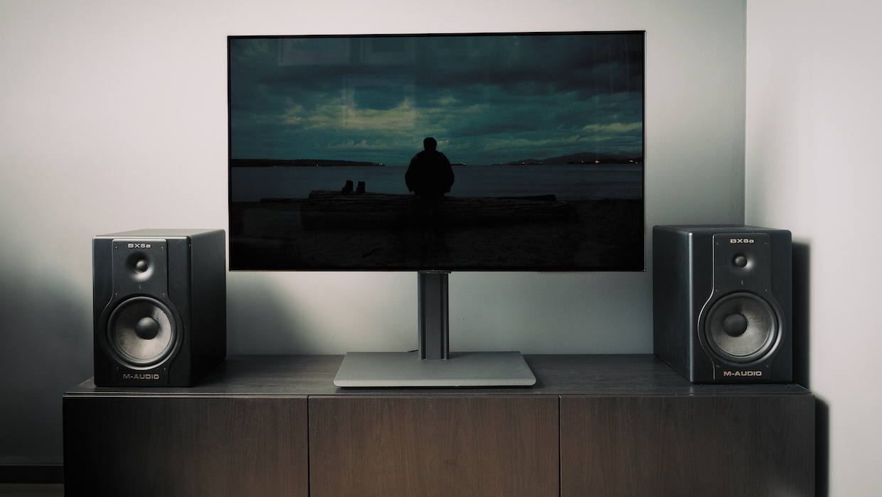 A television displaying na image during daytime with of a man on a dark beach in a living room.