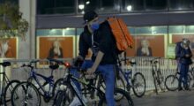 A bicycle messenger wearing a mask sets out on his trip at night.