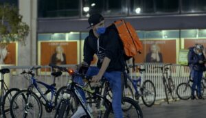 A bicycle messenger wearing a mask sets out on his trip at night.