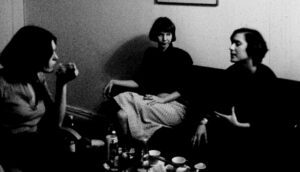 Three women sit in a living room having a discussion.