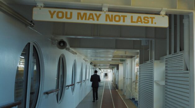 A man walks down the hallway of a long cruise ship.
