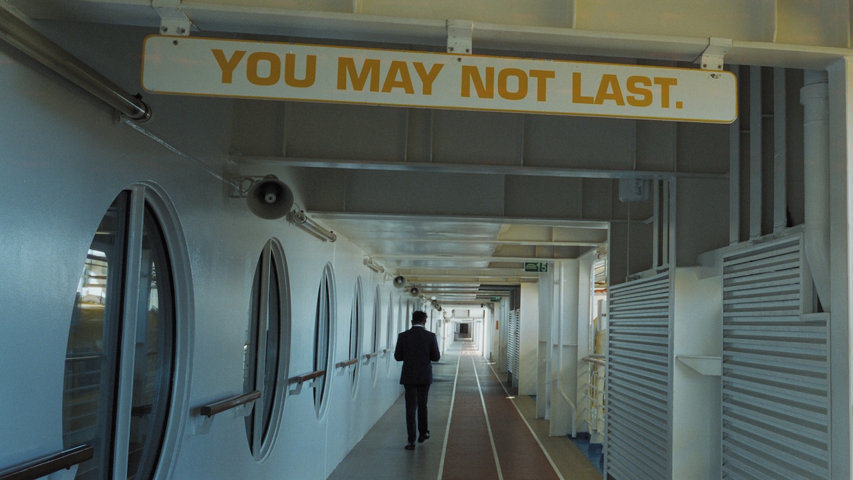 A man walks down the hallway of a long cruise ship.