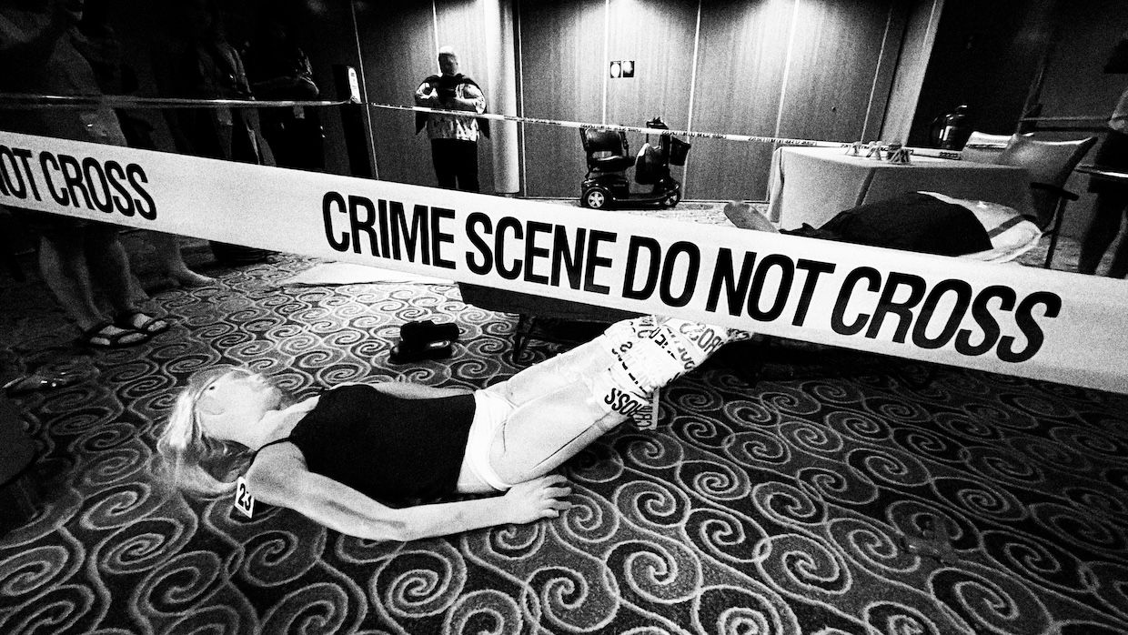 A mannequin simulating a corpse lies on the floor of a cruise ship made up to resemble a crime scene.