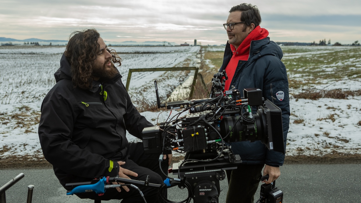 A cinematographer and film director stand around a film camera on a set.