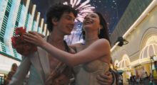 A young couple walk through Las Vegas underneath fireworks.