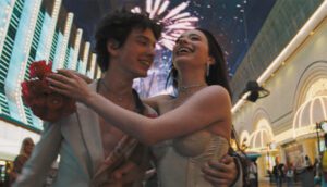 A young couple walk through Las Vegas underneath fireworks.